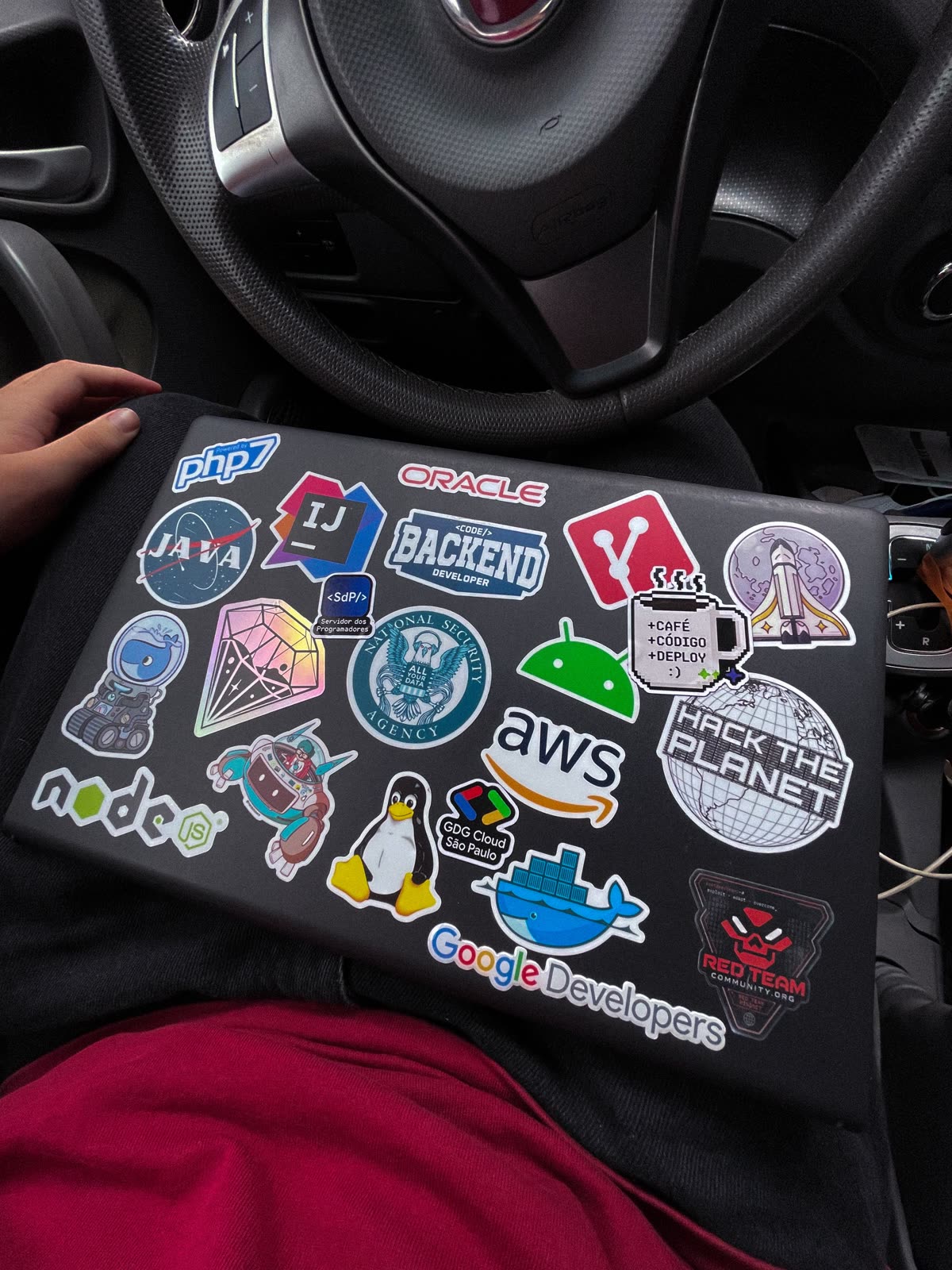 Tampa de notebook coberta de adesivos de tecnologia: Java, Oracle, AWS, Docker, Linux e Google Developers