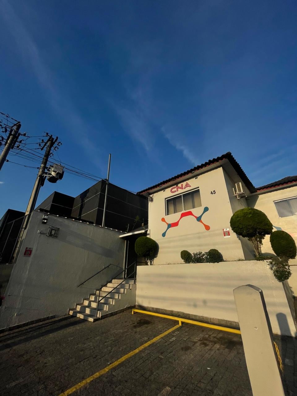Fachada de uma unidade da escola de idiomas CNA, sob céu azul